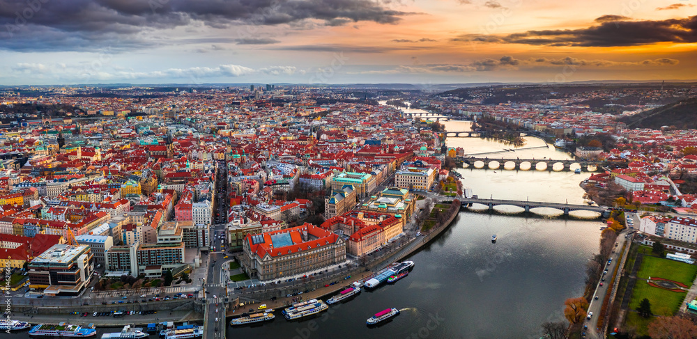 Obraz premium Prague, Czech Republic - Aerial panoramic drone view of city of Prague at dusk. Red rooftops, the famous Charles Bridge (Karluv most) and St. Francis Of Assisi Church and magical winter sunset and sky