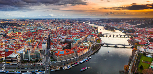 Prague, Czech Republic - Aerial panoramic drone view of city of Prague at dusk. Red rooftops, the famous Charles Bridge (Karluv most) and St. Francis Of Assisi Church and magical winter sunset and sky