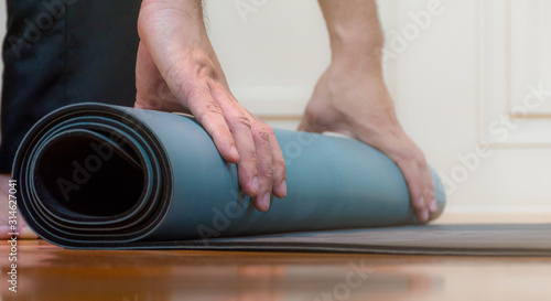The man is using his hands to roll green yoga