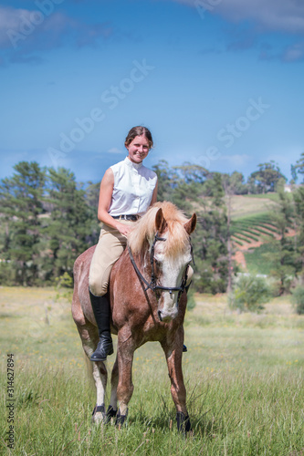 Portrait of a Girl smiling and sitting on her Sabino paint horse in the field both facing the camera full length.
