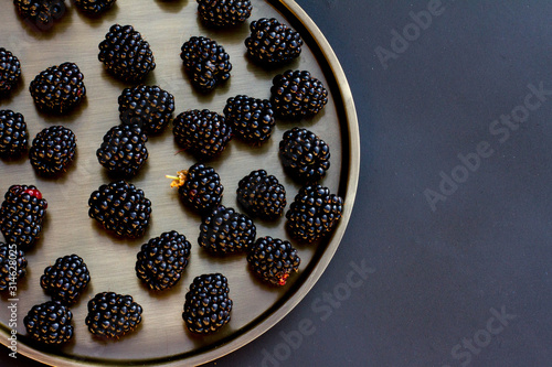 black ripe blackberries on a black background on a platter. the concept of healthy eating and gardening. black berry. benefits and vitamins.the view from the top. space for text. Dark blue blueberries