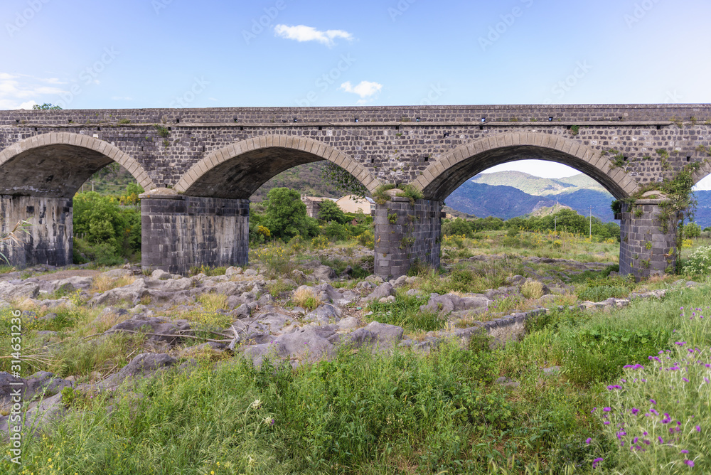 Old stone bridge over River Alcantara near Castiglione di Sicilia village, Sicily in Italy