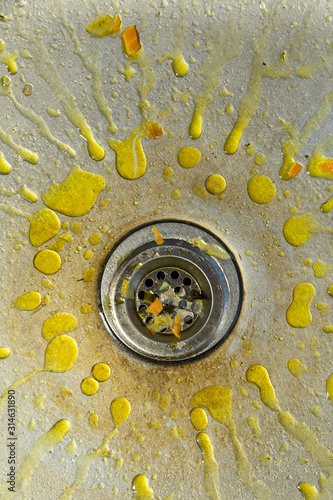A dirty and littered sink with yellow grease stains.