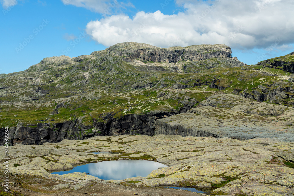 Lake landscape with clouds reflection, rocky mountain tundra, way to Trolltunga rock, Norway.