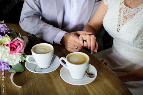 Wedding couple drink coffee and holding hands. Wedding card