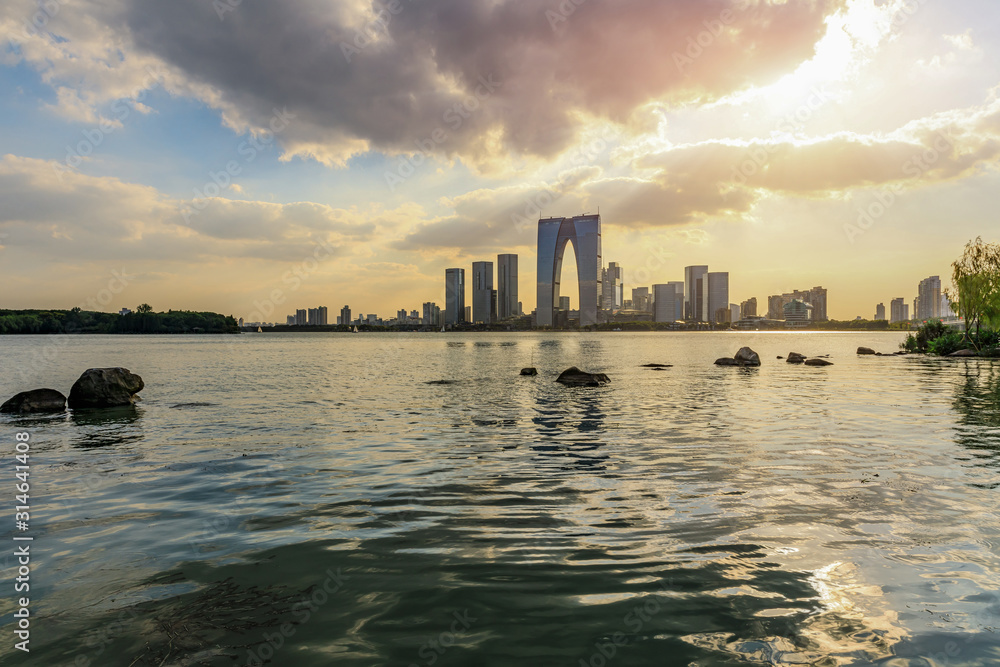 Beautiful city skyline and tranquil lake in Suzhou at sunset Beautiful city skyline and tranquil lake in Suzhou at sunset