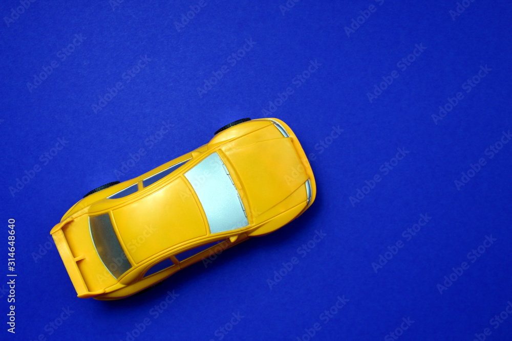 Yellow toy car photographed from above on a blue background