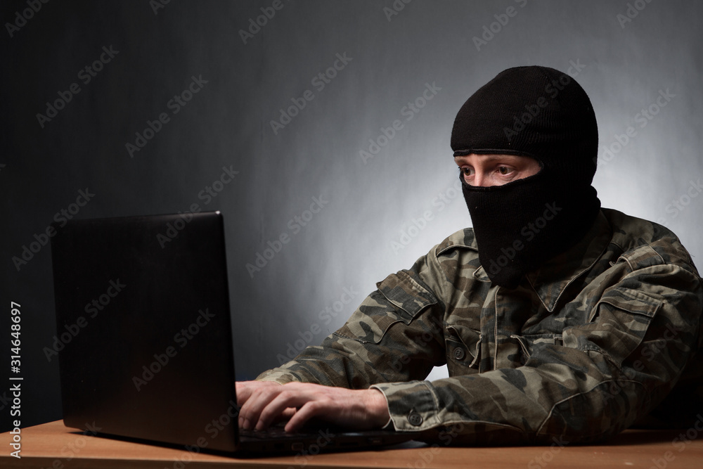 Masked cyber terrorist in military uniform hacking army intelligence Masked cyber terrorist in military uniform hacking army intelligence