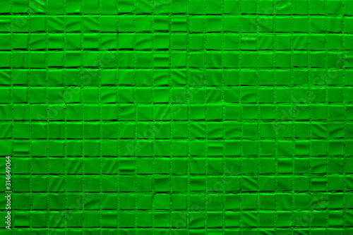 Uneven concrete wall with small green squares
