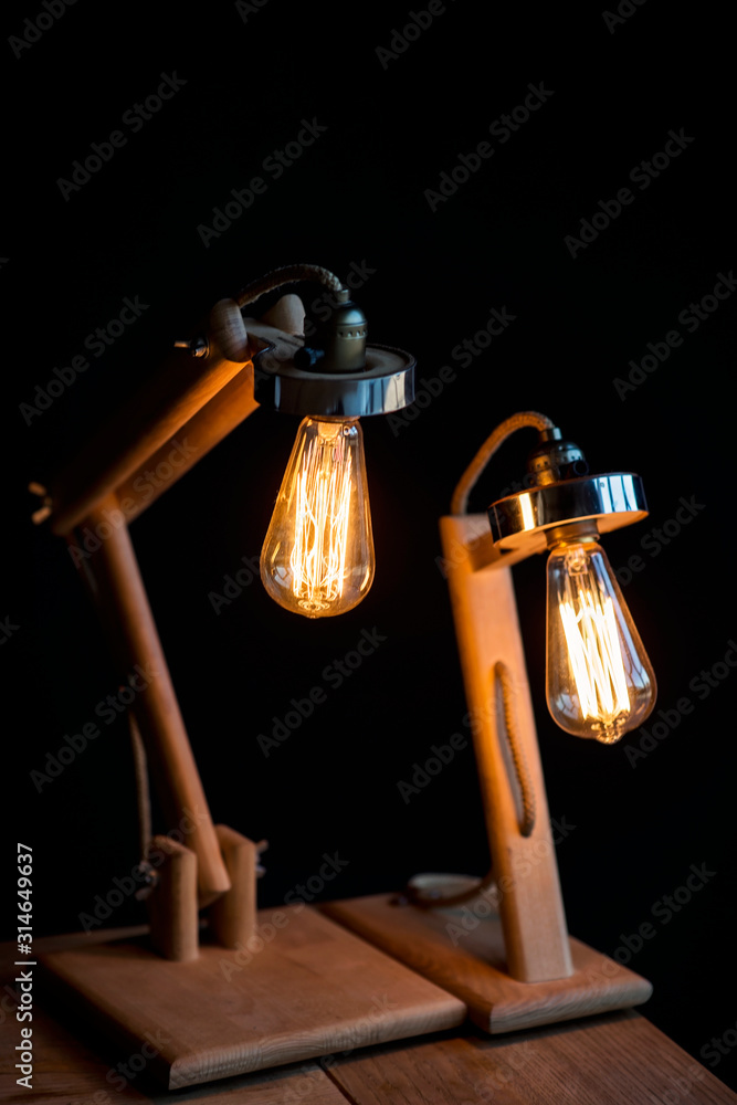 Two modern wooden designer table lamps on a black background. Soft focus. Interior Design.