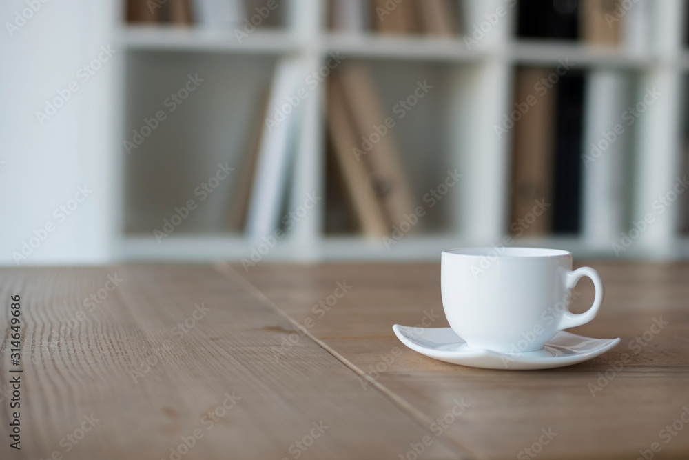 White cup and saucer with coffee on a wooden table in the office. Soft focus. Copy space White cup and saucer with coffee on a wooden table in the office. Soft focus. Copy space