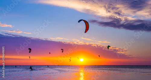 Kite-surfing against a beautiful sunset. Many silhouettes of kites in the sky. Travel concept. Artistic picture. Beauty world. Panorama photo
