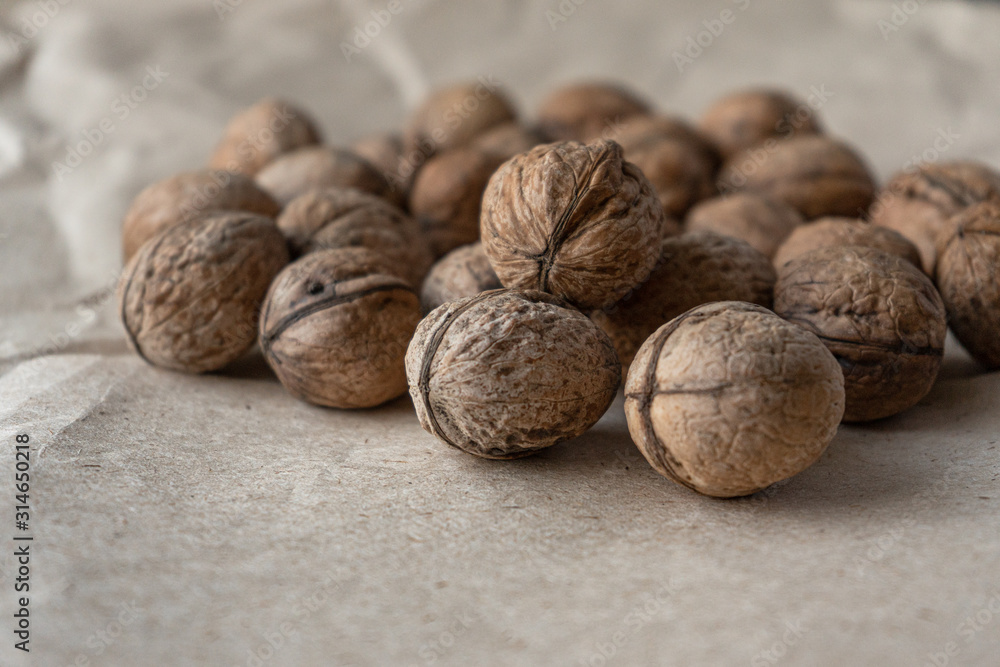 Horizontal handful of walnuts in the shell on an old mint kraft paper, a brown background, a warm beige pattern Horizontal handful of walnuts in the shell on an old mint kraft paper, a brown background, a warm beige pattern