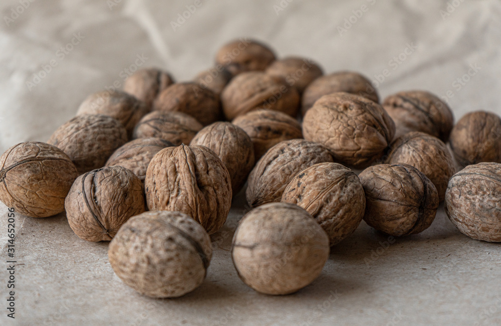 Horizontal handful of walnuts in the shell on an old mint kraft paper, a brown background, a warm beige pattern Horizontal handful of walnuts in the shell on an old mint kraft paper, a brown background, a warm beige pattern