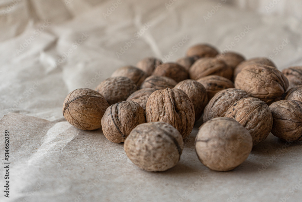 Horizontal handful of walnuts in the shell on an old mint kraft paper, a brown background, a warm beige pattern Horizontal handful of walnuts in the shell on an old mint kraft paper, a brown background, a warm beige pattern