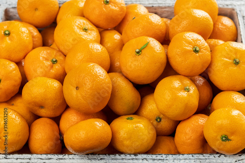 Fresh citrus fruit tangerines in a wooden box in the market close-up.