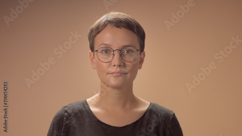 Caucasian woman with a short haircut wears a glasses. Monochrome beige styleof image photo