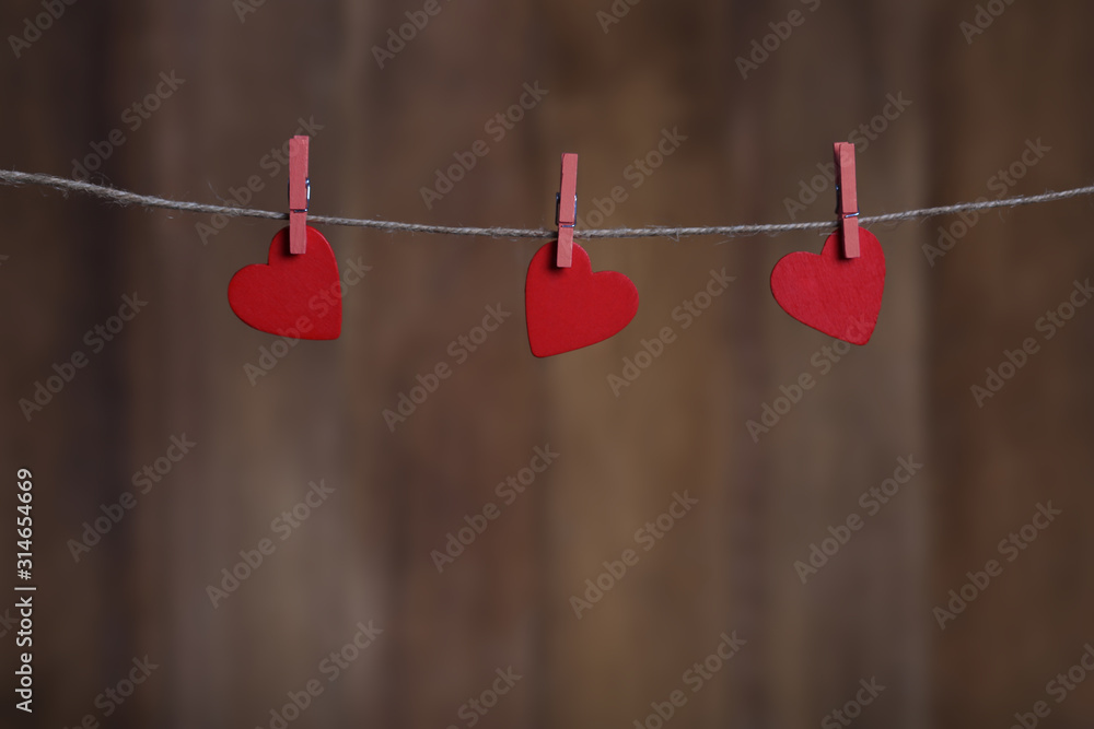 Valentine day greeting card with copy space and hearts pinned to rope on wooden background Valentine day greeting card with copy space and hearts pinned to rope on wooden background