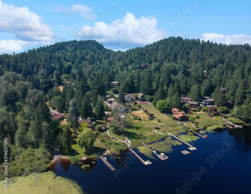 Photogenic Spring Lake on a bright clear day in summertime with trees reflecting in the water a blue sky and white clouds with lily pads dockside in Renton King County Washington State