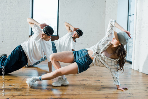 trendy multicultural dancers breakdancing in dance studio photo