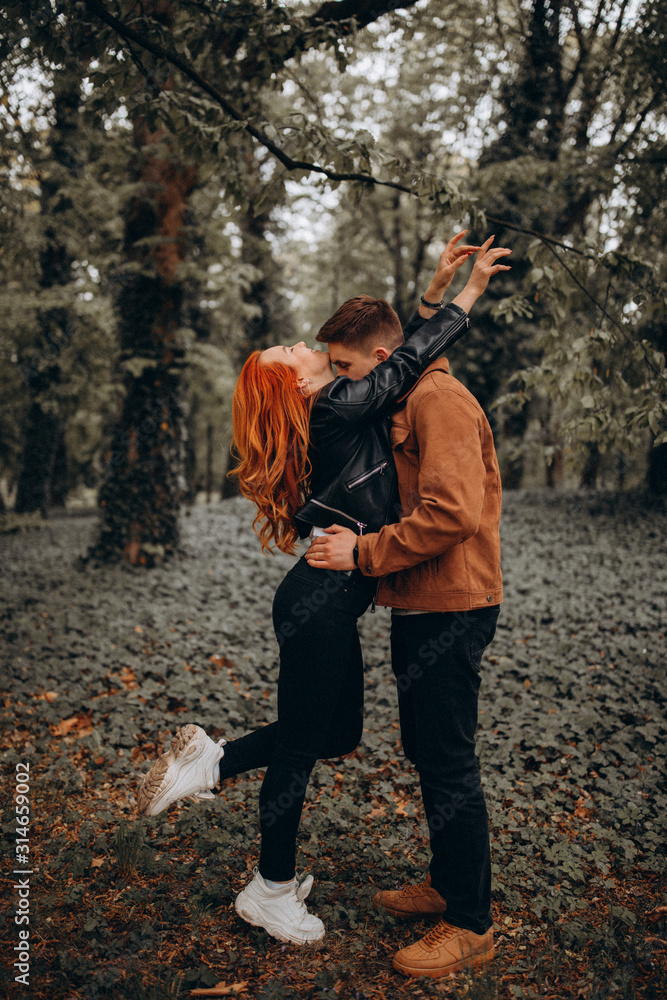 Fototapeta premium Romantic vacation of a guy and a girl in the autumn park. Fun games of a young couple in nature.