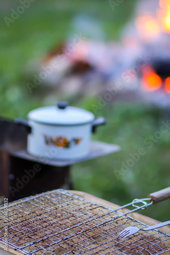 Fototapeta Naklejka Na Ścianę i Meble -  Meat on the grill and white pan on the brazier on bonfire background