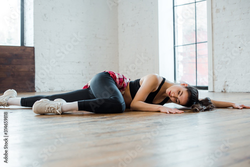 attractive girl lying on floor while dancing jazz funk in dance studio