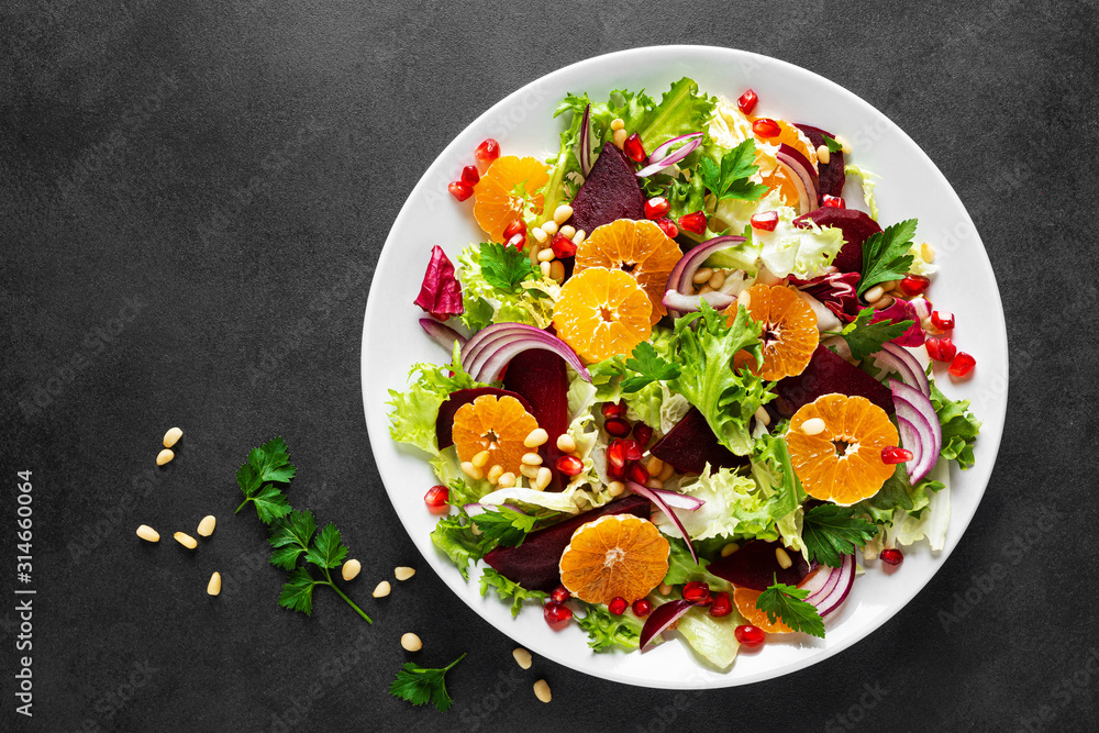 Christmas salad with boiled beet, red onion, tangerines, pomegranate, parsley, pine nuts and lettuce leaves Christmas salad with boiled beet, red onion, tangerines, pomegranate, parsley, pine nuts and lettuce leaves