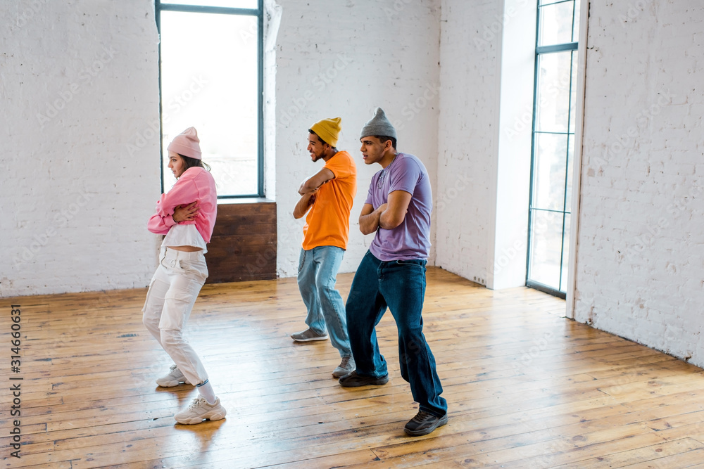 stylish girl with crossed arms breakdancing with handsome multicultural men in hats stylish girl with crossed arms breakdancing with handsome multicultural men in hats