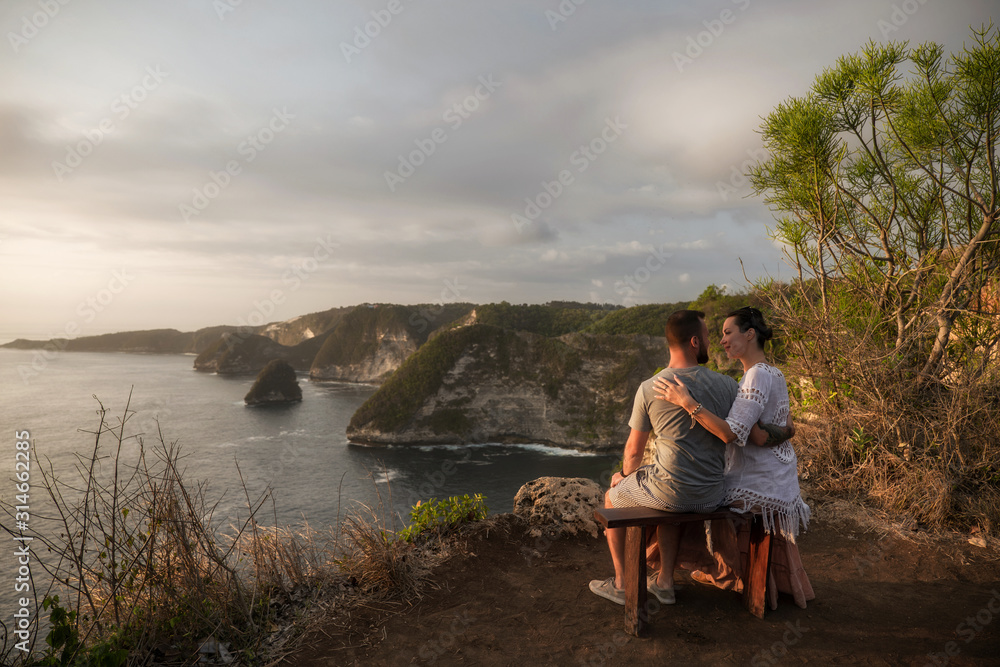 Couple enjoying view from Banah Cliff of Nusa Penida island, Indonesia