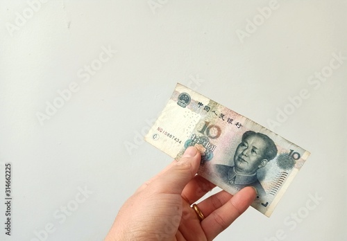 Chinese currency that a man held in his hand with a white background