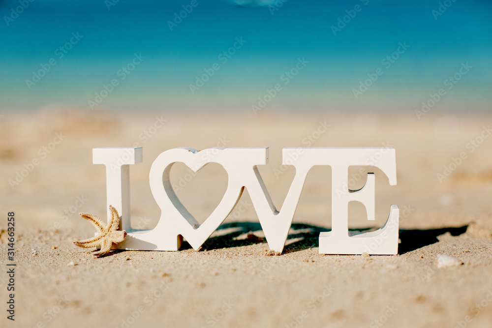 Wooden letters love on a sandy beach overlooking the blue sea