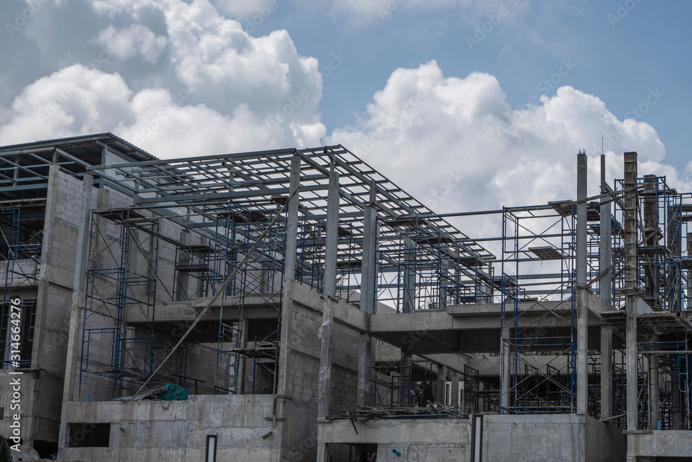 Building and Construction Site in progress. Building construction site against cloudy sky. Metal construction of unfinished building on construction of multi storage building. Building and Construction Site in progress. Building construction site against cloudy sky. Metal construction of unfinished building on construction of multi storage building.