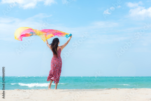Summer Holiday. Lifestyle asian woman raise hands with wearing dress fashion summer trips standing chill on the sandy ocean beach. Happy people enjoy and relax vacation. Lifestyle and Travel Concept.
