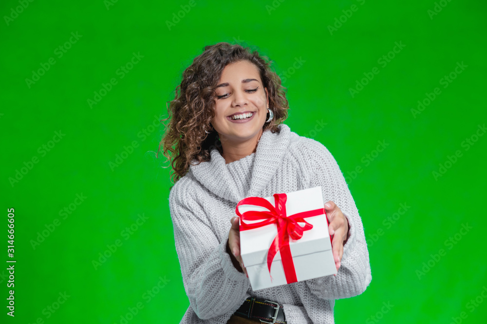 Christmas woman holding Christmas gifts in her arms wearing warm woolen sweater isolated on green background. Christmas woman holding Christmas gifts in her arms wearing warm woolen sweater isolated on green background.