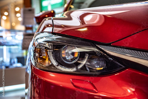 Modern red car headlight close-up. © Denis Rozhnovsky