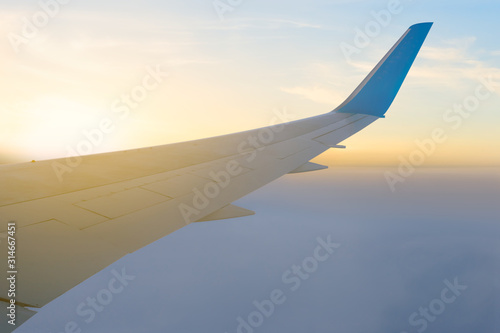 view from an airplane to a dense clouds below at the sunrise, travel background
