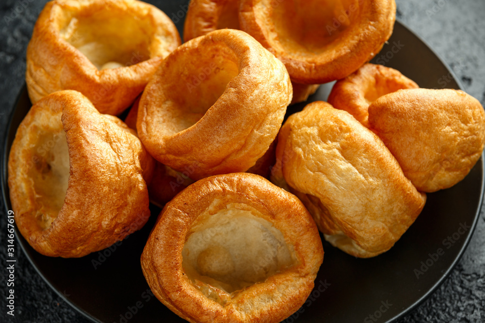 Traditional English Yorkshire pudding side dish on black plate and background Traditional English Yorkshire pudding side dish on black plate and background