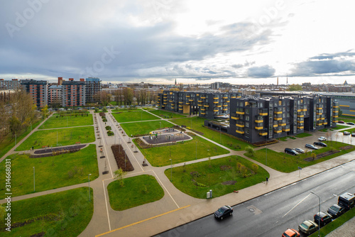 Cityscape in cloudy day. View from the top. Green grass on the courtyard.