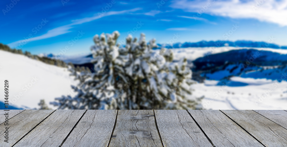 wooden display shelf table top against blurred winter mountain panorama snow covered mountains with pine tree