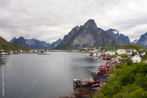 The city of Reine in Lofoten/Norway. Long exposure shot with overcast scenery. The famous Mount Olstind and snow covered mountains in the background. Traveling and Norwegian concept.