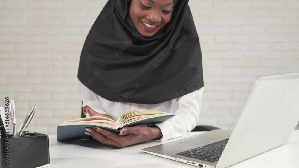 African woman turning pages in notebook. African woman turning pages in notebook.