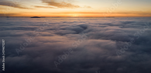 Beautiful panoramic sunrise above clouds from airplane perspective.