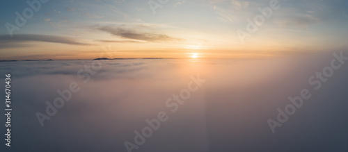 Beautiful panoramic sunrise above clouds from airplane perspective. © frankenfotograf