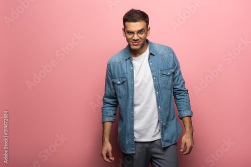 Handsome tricky man looking at camera on pink background