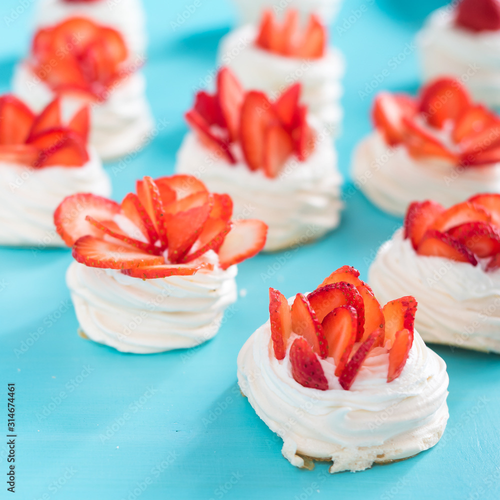 Beautiful pavlova cakes with strawberries on a blue background. Selective focus. Tasty sweet breackfast. Wedding morning. Meringue with cream. Beautiful pavlova cakes with strawberries on a blue background. Selective focus. Tasty sweet breackfast. Wedding morning. Meringue with cream.