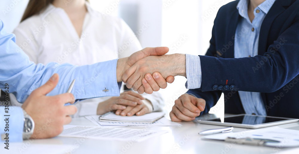 Business people shaking hands at meeting or negotiation, close-up. Group of unknown businessmen and women in modern office. Teamwork, partnership and handshake concept, toned picture Business people shaking hands at meeting or negotiation, close-up. Group of unknown businessmen and women in modern office. Teamwork, partnership and handshake concept, toned picture