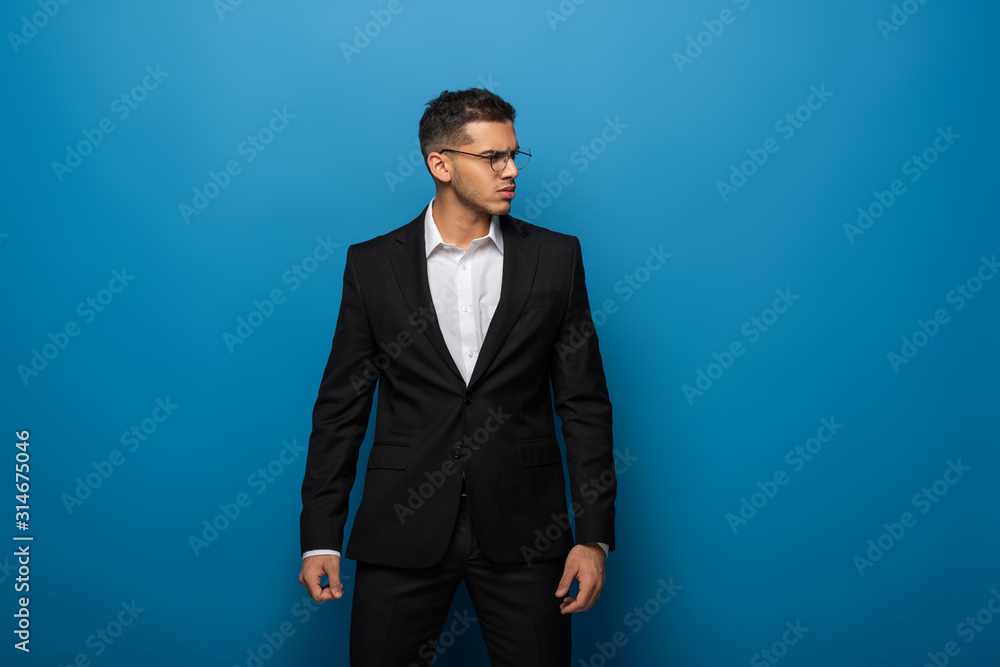 Handsome businessman looking away on blue background Handsome businessman looking away on blue background