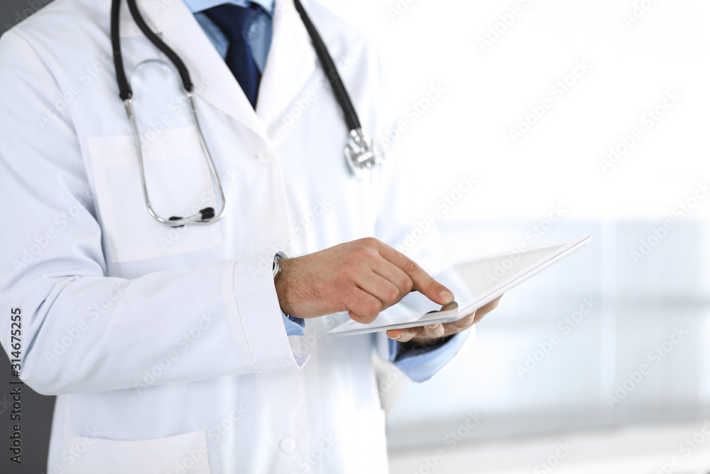 Doctor man using tablet computer for network research or virtual disease treatment, hands close-up. Perfect medical service in clinic. Modern medicine, medic data and healthcare concepts. Toned Doctor man using tablet computer for network research or virtual disease treatment, hands close-up. Perfect medical service in clinic. Modern medicine, medic data and healthcare concepts. Toned