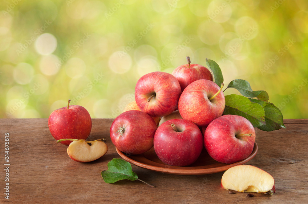 Ripe red-yellow apples with leaves in a clay plate on a wooden table. Whole and sliced fruits. Harvest fruit trees. Ripe red-yellow apples with leaves in a clay plate on a wooden table. Whole and sliced fruits. Harvest fruit trees.